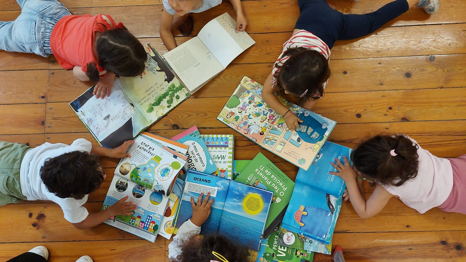 Crianças deitadas no cão a lerem livros